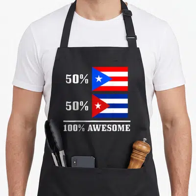 Rico cuba pride apron - Stacked Puerto Rican and Cuban flags beside 50% text above 100% Awesome label — shown on a black cotton canvas apron against a white background