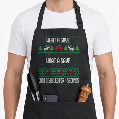 Save game aprons - Pixel ugly sweater pattern with what a save text and reindeer gift boxes — shown on a black cotton canvas apron against a white background