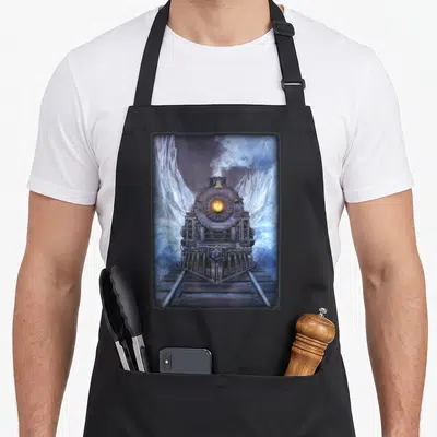 Train polar apron - Realistic steam locomotive facing forward with smoke and snowy mountains in dark grey, blue, white — shown on a black cotton canvas apron against a white background