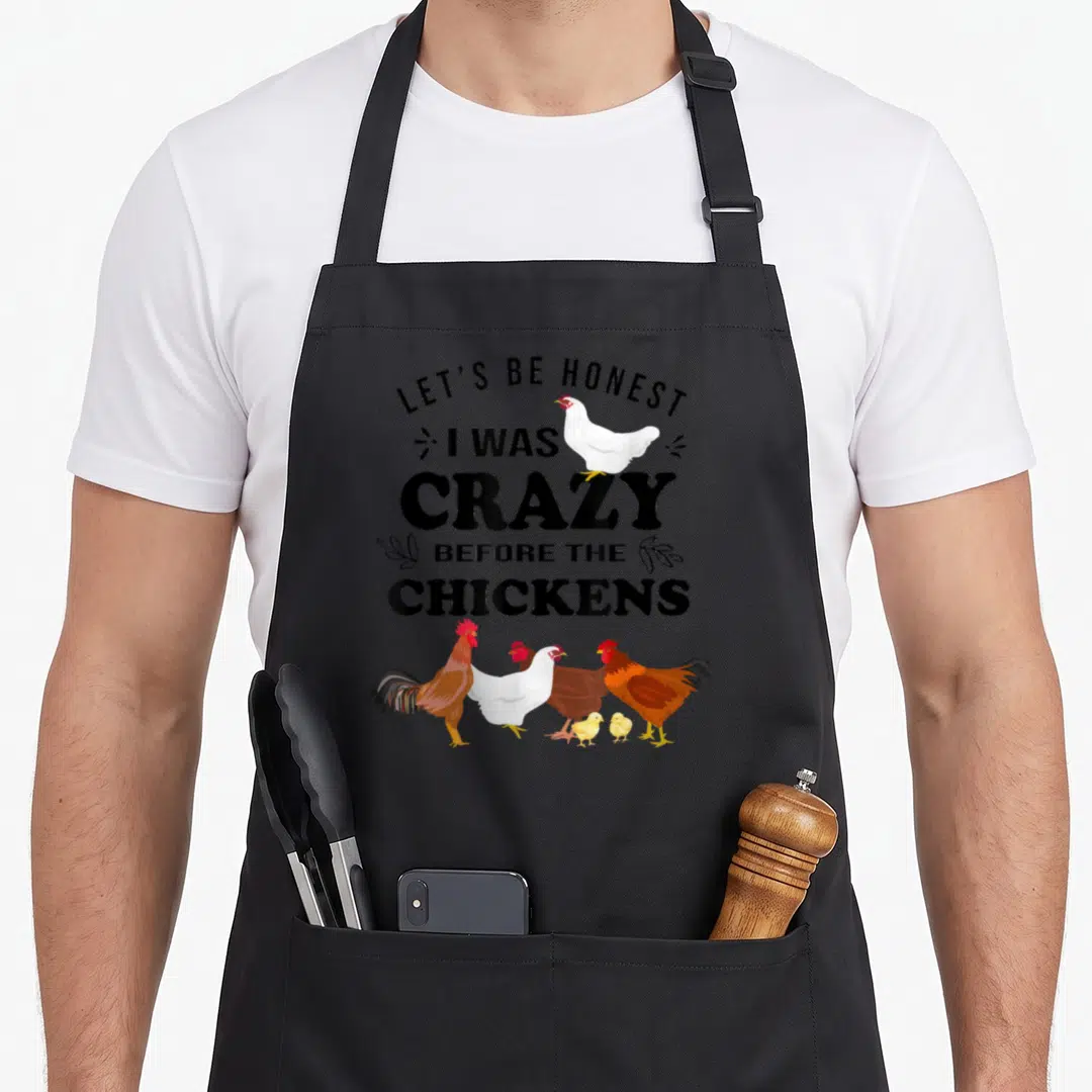 Honest chicken apron - Text LET'S BE HONEST I WAS CRAZY BEFORE THE CHICKENS with cartoon chickens and chicks — shown on a black cotton canvas apron against a white background