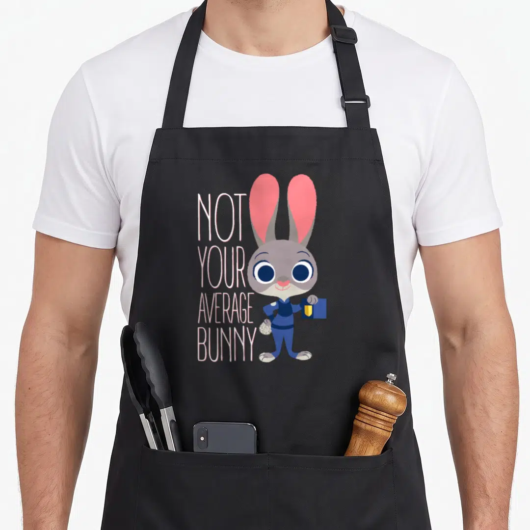 Hopp bunny apron - Stacked white text Not Your Average Bunny beside grey cartoon bunny holding blue tablet — shown on a black cotton canvas apron against a white background