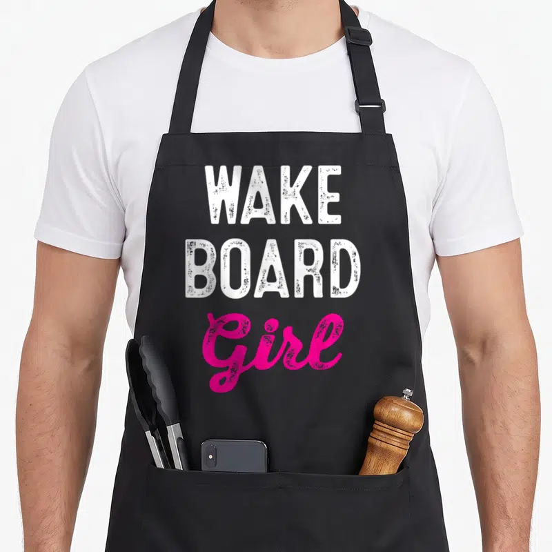 Wakeboard wakeboarding life apron - Stacked white WAKE BOARD text above pink script Girl typography — shown on a black cotton canvas apron against a white background