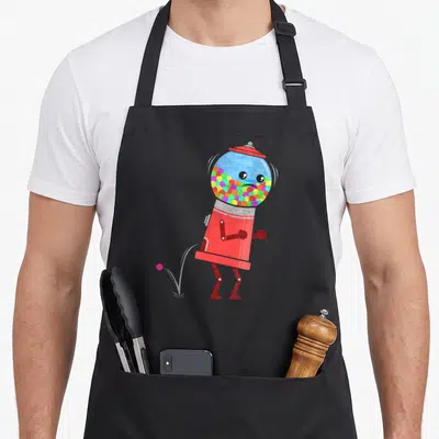 Chewing old fashioned aprons - Cartoon red gumball machine facing left with pink ball on ground and multi-colored balls — shown on a black cotton canvas apron against a white background
