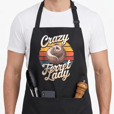 Sunset crazy ferret lady apron - Curled brown ferret on striped retro sun with Crazy Ferret Lady text — shown on a black cotton canvas apron against a white background