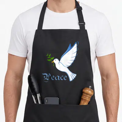 Peace dove apron - White cartoon dove holding green olive branch above blue Peace text — shown on a black cotton canvas apron against a white background