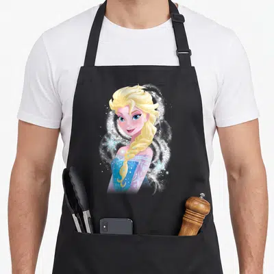Snowflake princess apron - Cartoon Elsa with blonde braid, blue dress, white sparkles, and light blue snowflakes — shown on a black cotton canvas apron against a white background