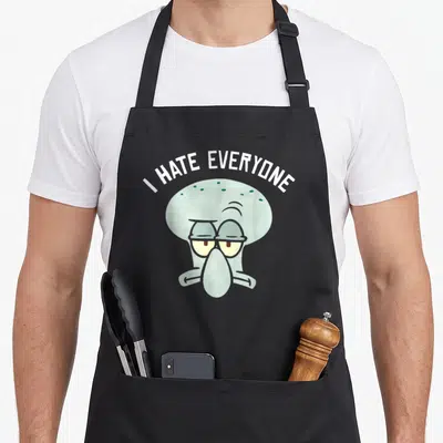 Squarepant crazy squid lady apron - Arched I HATE EVERYONE text above a blue-grey cartoon squid head — shown on a black cotton canvas apron against a white background