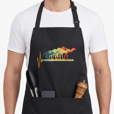 Heartbeat camel apron - Five retro camels in blue, green, yellow, orange, and red standing on a heartbeat pulse line — shown on a black cotton canvas apron against a white background