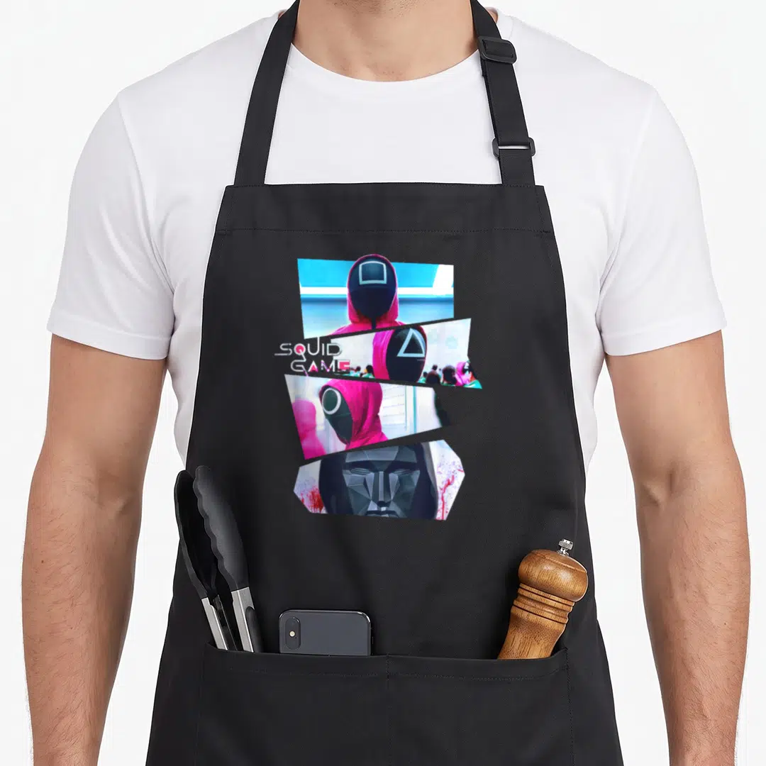 Guard crazy squid man apron - Four diagonal photo slices of masked figures in pink and black with SQUID GAME text — shown on a black cotton canvas apron against a white background