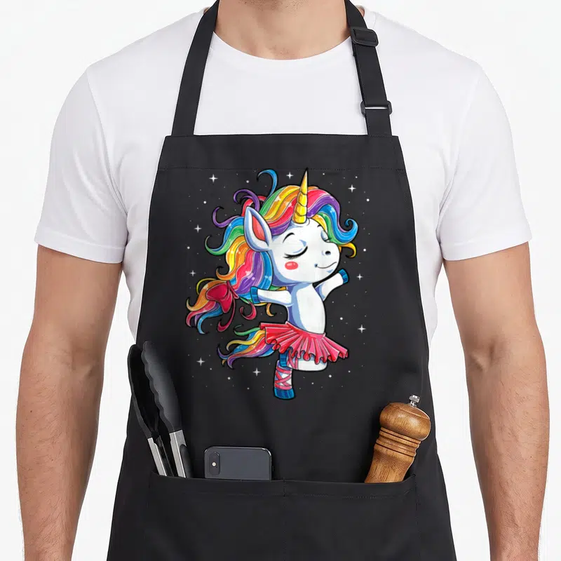 Ballet ballerina apron - Cartoon unicorn in pink tutu with rainbow mane and scattered stars on grey background — shown on a black cotton canvas apron against a white background