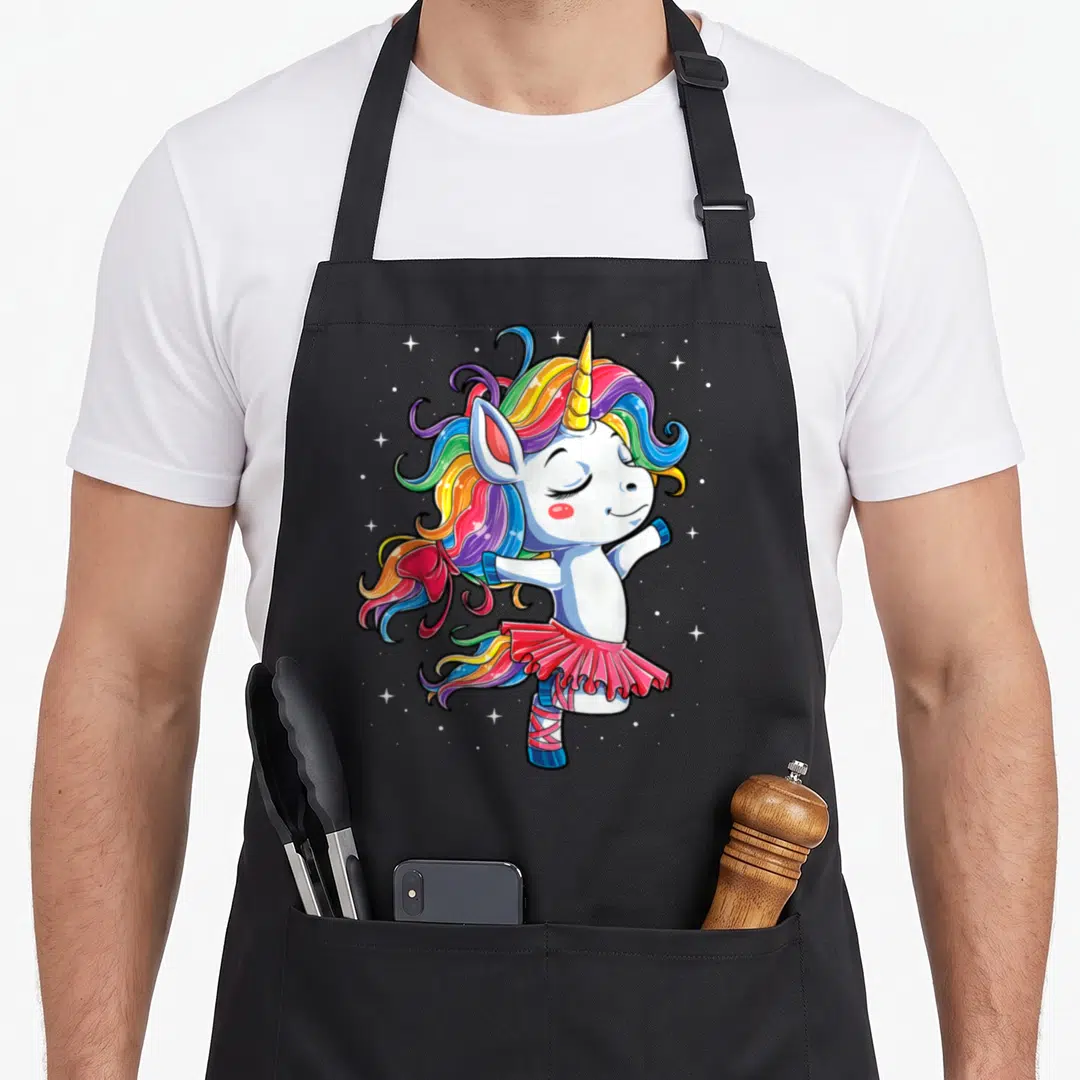 Ballet ballerina apron - Cartoon unicorn in pink tutu with rainbow mane and scattered stars on grey background — shown on a black cotton canvas apron against a white background