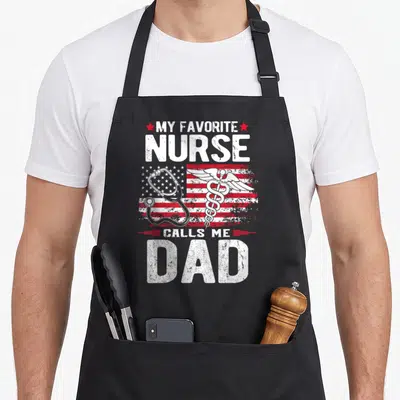 Father nurses apron - Distressed My Favorite Nurse Calls Me Dad text with stethoscope and caduceus over flag — shown on a black cotton canvas apron against a white background