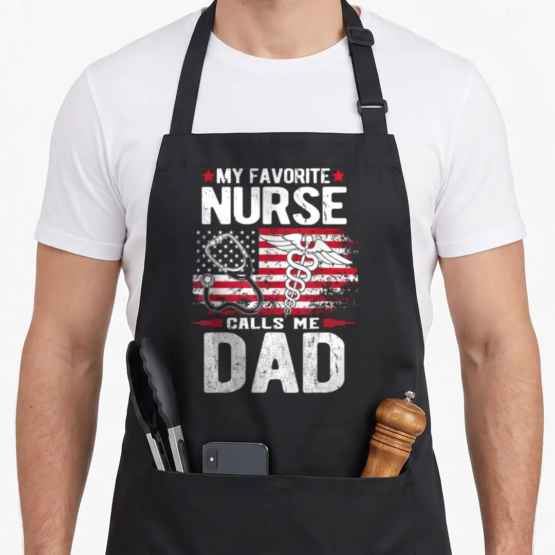 Father nurses apron - Distressed My Favorite Nurse Calls Me Dad text with stethoscope and caduceus over flag — shown on a black cotton canvas apron against a white background
