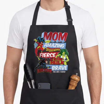 Funny amazing aprons - Retro comic art Mom Spider-Woman She-Hulk Black Widow text red blue green yellow — shown on a black cotton canvas apron against a white background