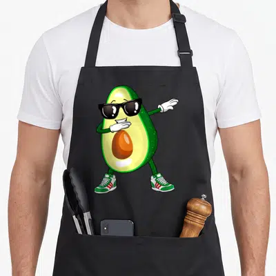 Dabbing avocado apron - Cartoon avocado wearing sunglasses and sneakers performing a dance move in green and yellow — shown on a black cotton canvas apron against a white background