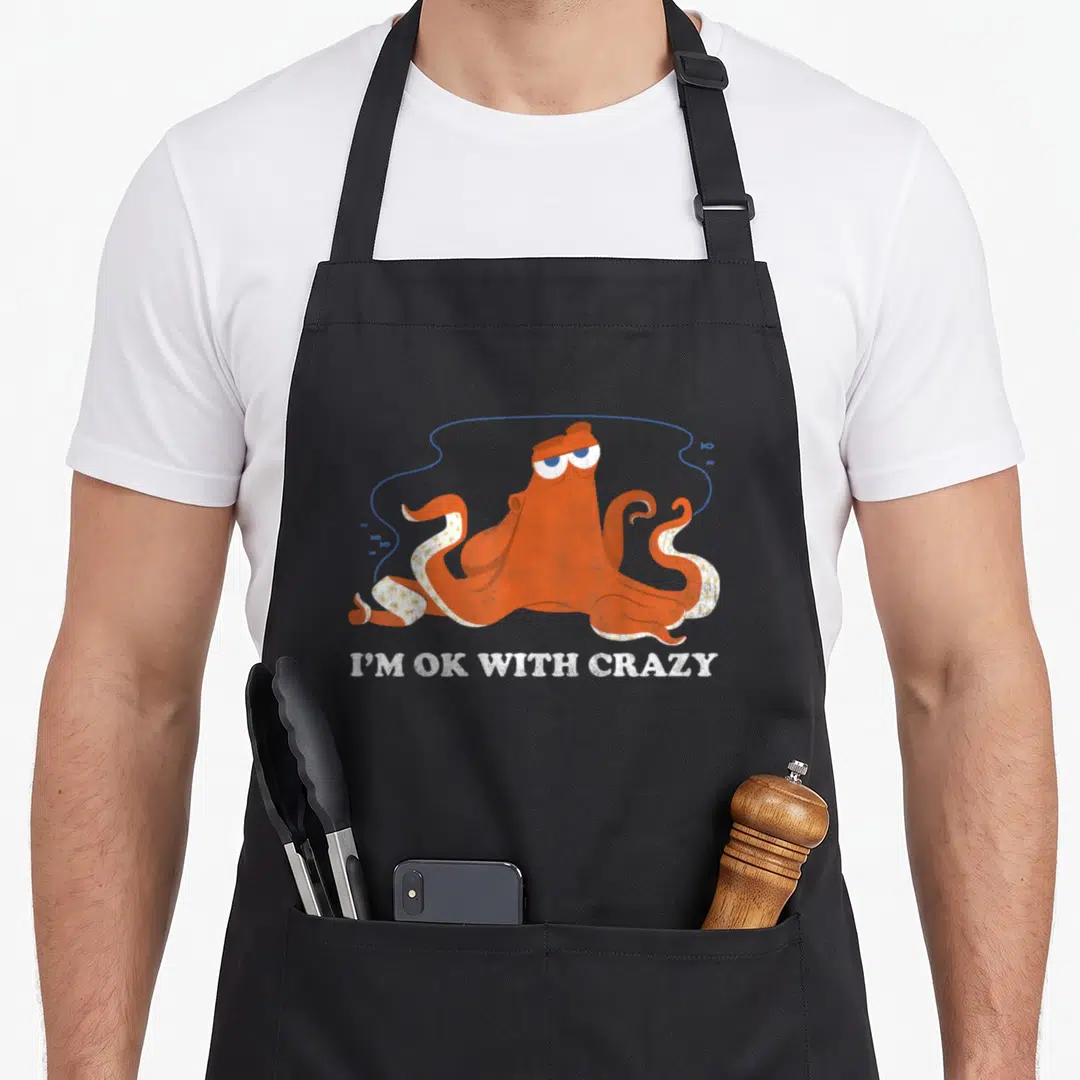 Finding crazy octopus man apron - Orange octopus with blue line and small fish, white text I'M OK WITH CRAZY below — shown on a black cotton canvas apron against a white background