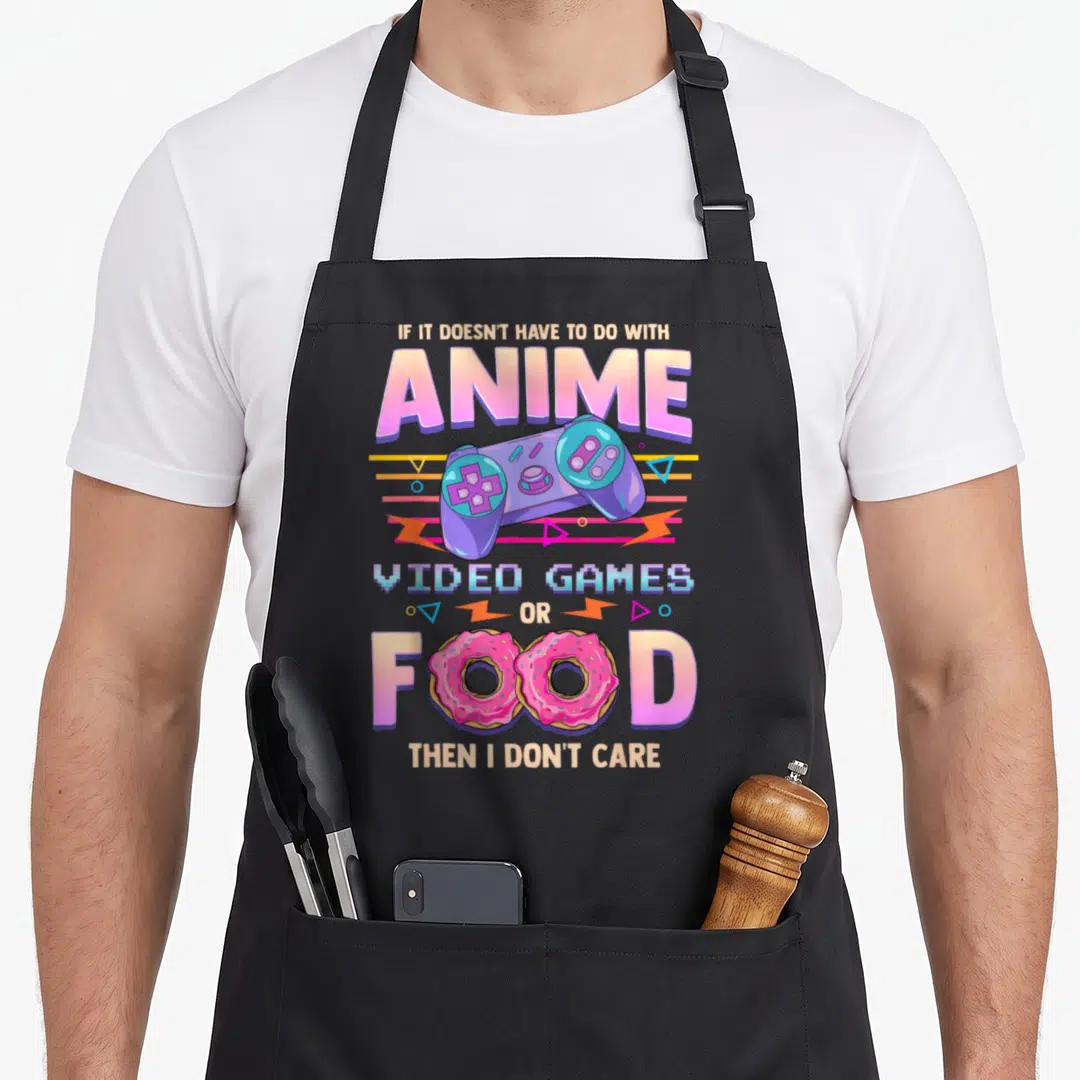 Anime video game apron - Purple controller and pink donuts replacing letters in stacked text reading IF IT DOESN'T HAVE — shown on a black cotton canvas apron against a white background