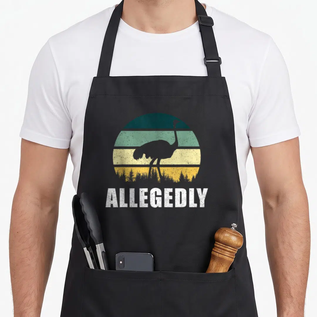 Funny allegedly ostrich apron - Retro striped sun with ostrich silhouette and white ALLEGEDLY text below — shown on a black cotton canvas apron against a white background