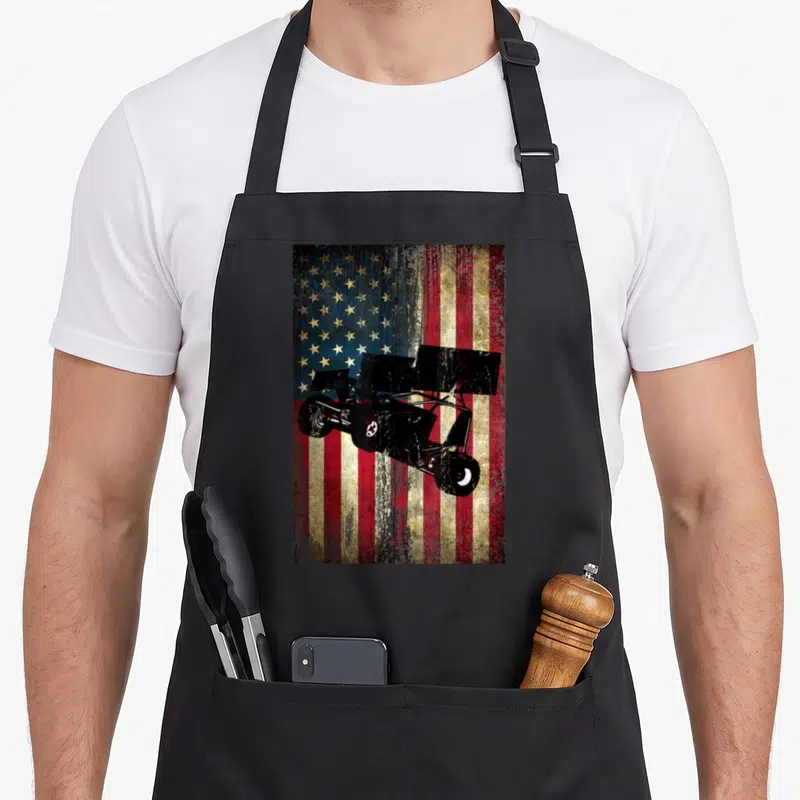 Distressed track apron - Black sprint car silhouette on distressed red white blue USA flag background — shown on a black cotton canvas apron against a white background