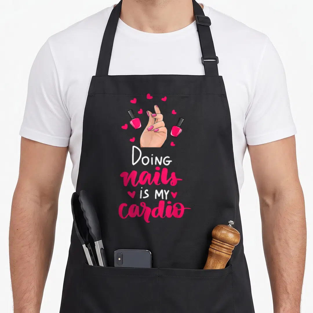 Doing manicurist apron - Cartoon hand with pink nails surrounded by polish bottles and hearts above stacked text — shown on a black cotton canvas apron against a white background