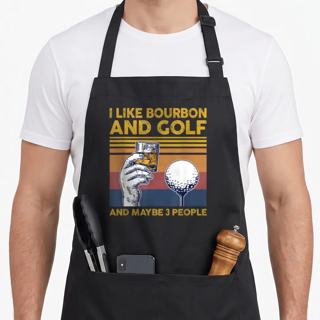 Bourbon golf apron - Retro graphic of hand holding glass next to golf ball on tee with yellow and blue striped — shown on a black cotton canvas apron against a white background