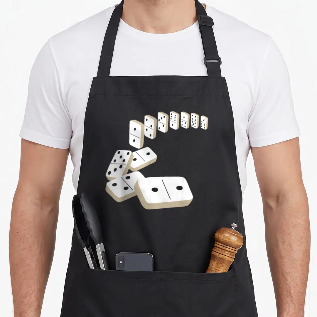Dominoe modern apron - Realistic white dominoes falling in a curved line on a black background — shown on a black cotton canvas apron against a white background