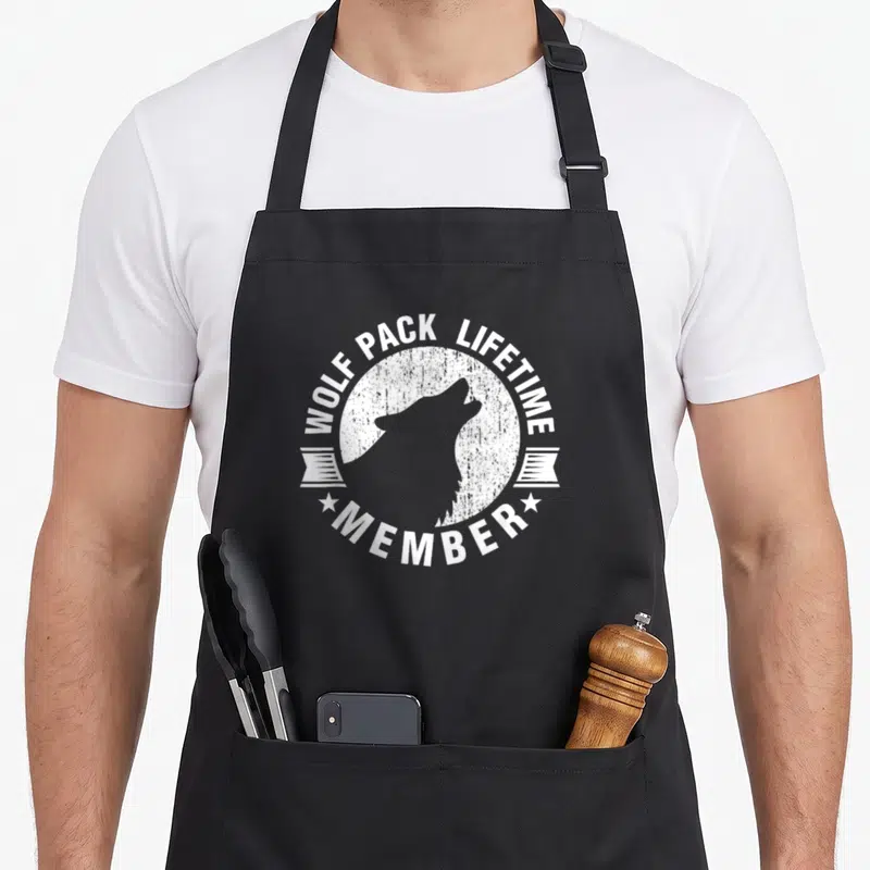 Lifetime distressed apron - Wolf pack lifetime member badge with grey wolf silhouette inside distressed white circle — shown on a black cotton canvas apron against a white background