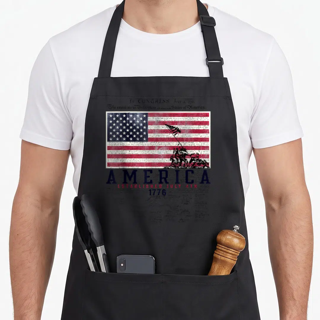 Established 4th of july apron - Declaration of Independence text background with red white blue flag and AMERICA — shown on a black cotton canvas apron against a white background