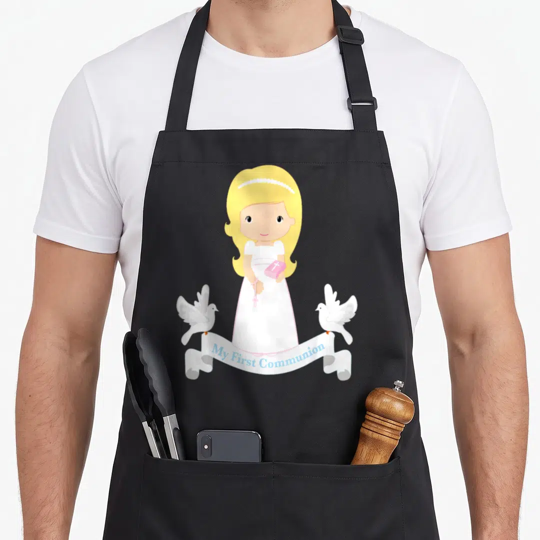 Daughter communion aprons - Cartoon girl holding pink bible and rosary flanked by two doves with My First Communion — shown on a black cotton canvas apron against a white background