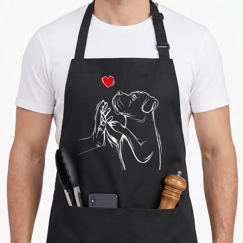 Wifey cane apron - White line art of dog head reaching to hand with red heart above — shown on a black cotton canvas apron against a white background