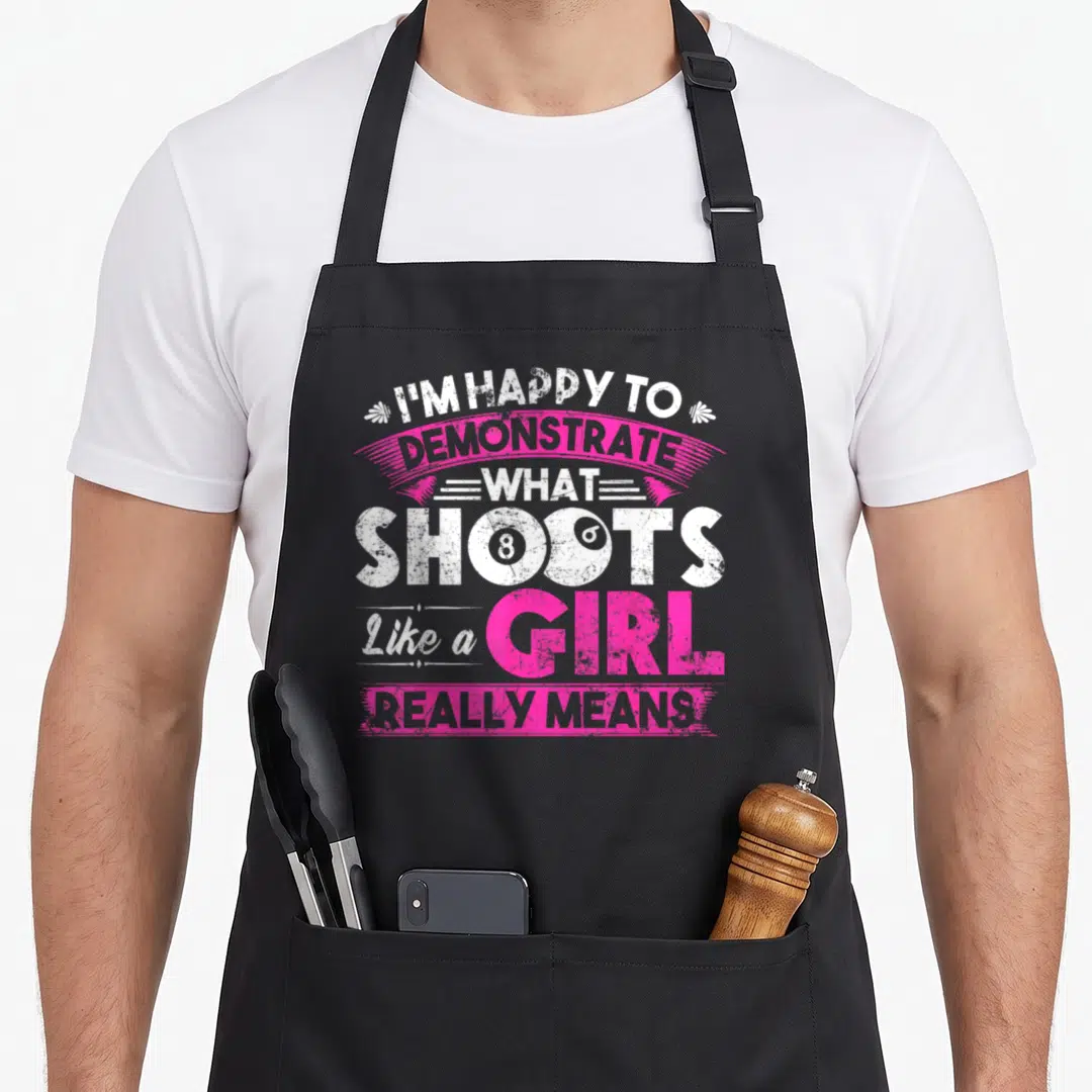 Cute pool billiards apron - Stacked white and pink text I'm Happy To Demonstrate What Shoots Like A Girl Really Means — shown on a black cotton canvas apron against a white background