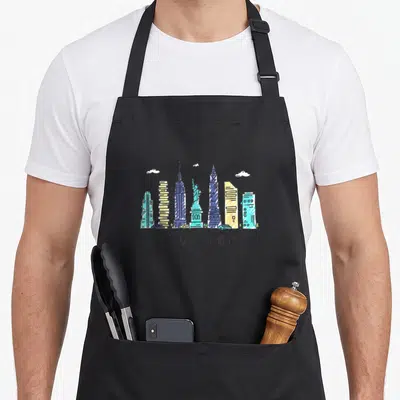 Nyc souvenir new york apron - Cartoon New York skyline illustration with Statue of Liberty and text - NEW YORK - — shown on a black cotton canvas apron against a white background