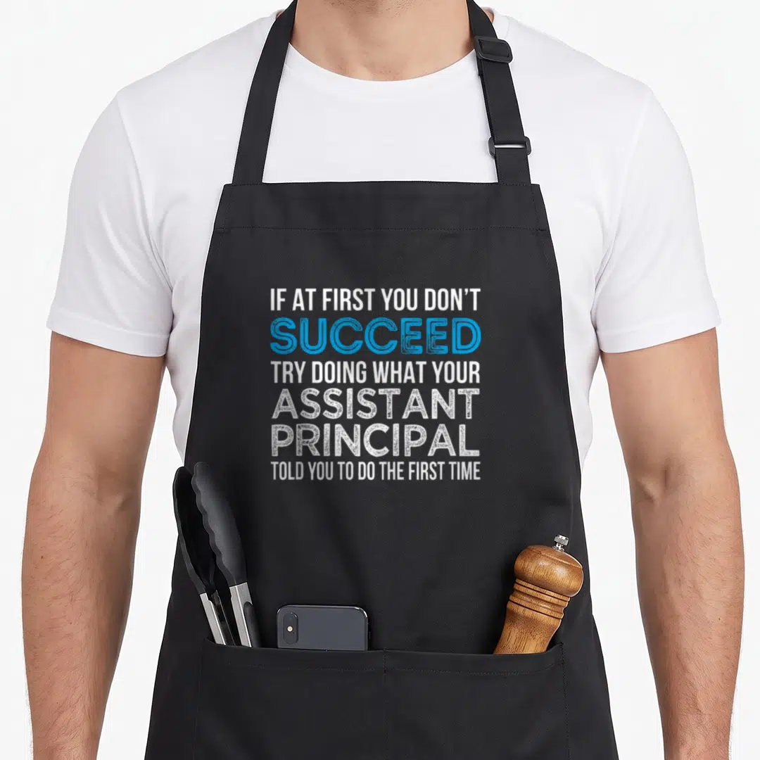 Cute assistant principal apron - Stacked white and blue text reading if at first you don't succeed try doing what your — shown on a black cotton canvas apron against a white background