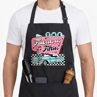Fifty 1950s apron - Light blue car over checkerboard with pink shape reading The Fabulous Fifties 1956 Rock n Roll — shown on a black cotton canvas apron against a white background