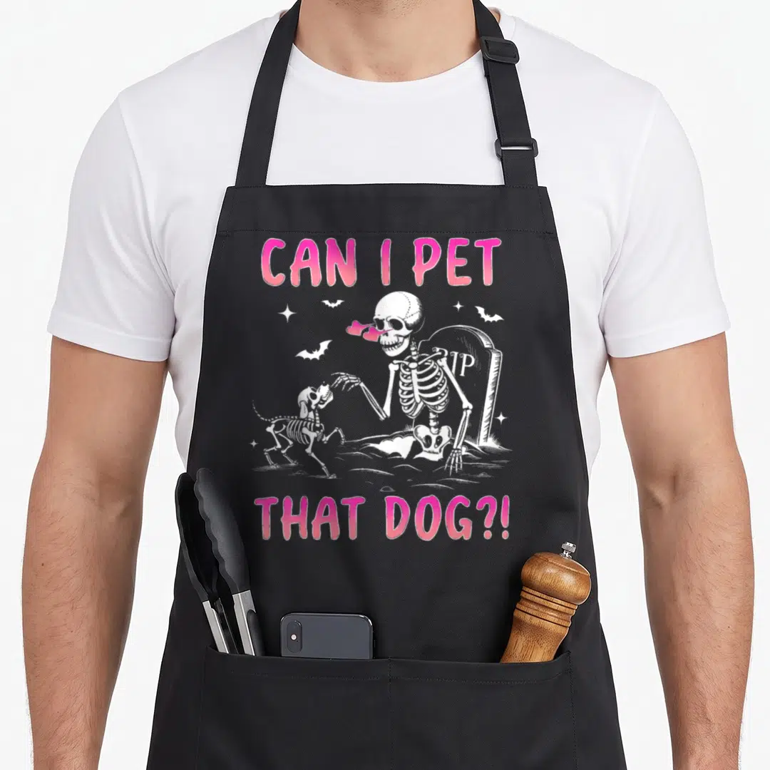 Pet cheap halloween aprons - Cartoon skeleton reaching for skeleton dog with pink text and tombstone — shown on a black cotton canvas apron against a white background