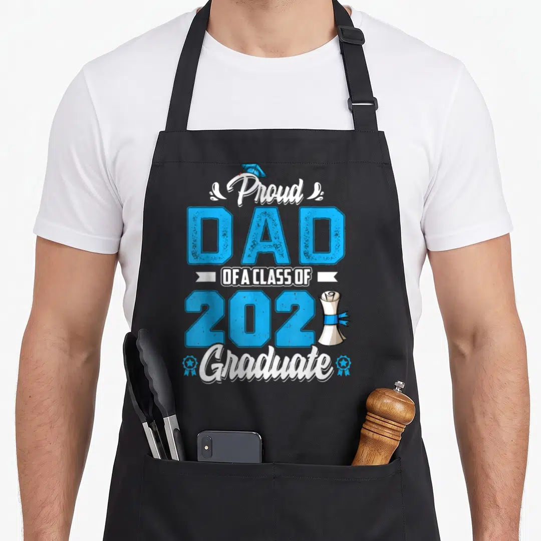 Proud class senior dad apron - Blue and white 2021 Graduate text with cap, diploma scroll, and ribbon graphics on black — shown on a black cotton canvas apron against a white background