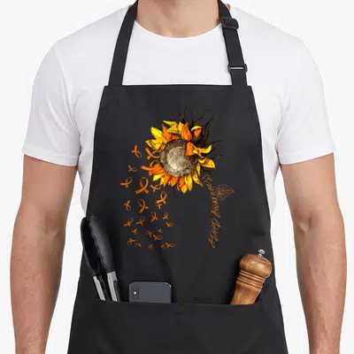 Adhd sunflower apron - Realistic sunflower with orange ribbons and vertical ADHD Awareness text — shown on a black cotton canvas apron against a white background