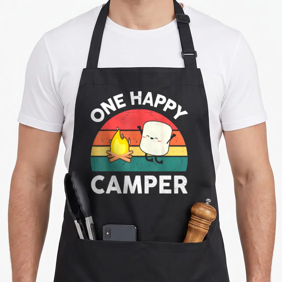 Camper toddler camping apron - ONE HAPPY CAMPER text over striped sun with jumping marshmallow and campfire — shown on a black cotton canvas apron against a white background