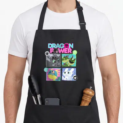 Power dragon apron - Stacked DRAGON POWER text above four square cartoon dragon heads with colored borders and corner — shown on a black cotton canvas apron against a white background