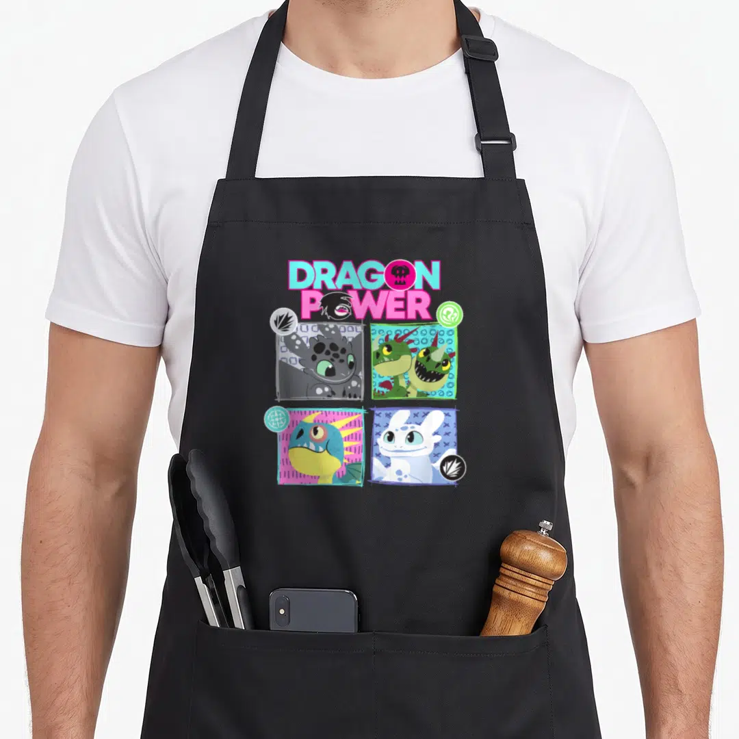 Power dragon apron - Stacked DRAGON POWER text above four square cartoon dragon heads with colored borders and corner — shown on a black cotton canvas apron against a white background