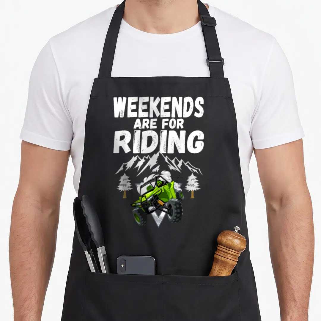 Riding atv apron - WEEKENDS ARE FOR RIDING text over lime green UTV with two white pine trees and mountain peaks — shown on a black cotton canvas apron against a white background
