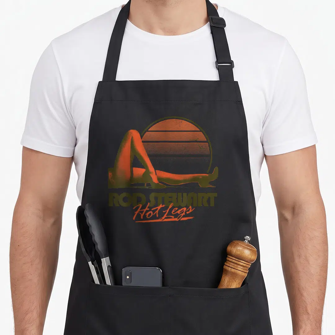 Rod leg apron - Retro graphic of legs against striped sun with Rod Stewart Hot Legs text below — shown on a black cotton canvas apron against a white background