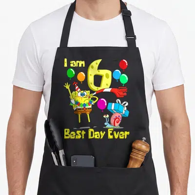 Age bday apron - SpongeBob SquarePants blowing horn with I am 6 text and balloons — shown on a black cotton canvas apron against a white background