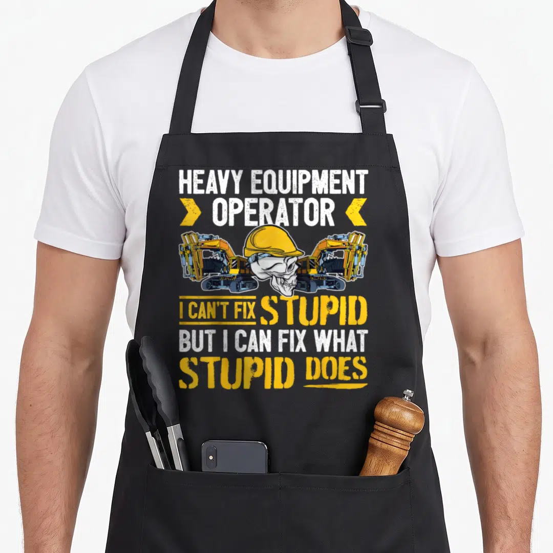 Fix heavy canvas aprons - Skull in hard hat between two excavators with yellow and white text — shown on a black cotton canvas apron against a white background