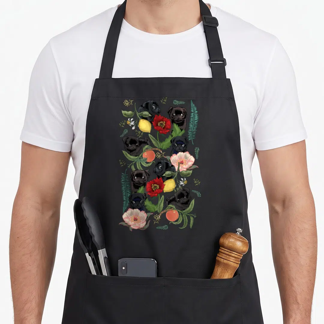 Botanical pug apron - Vertical cluster of cartoon black pugs mixed with red, pink, yellow flowers and green leaves — shown on a black cotton canvas apron against a white background