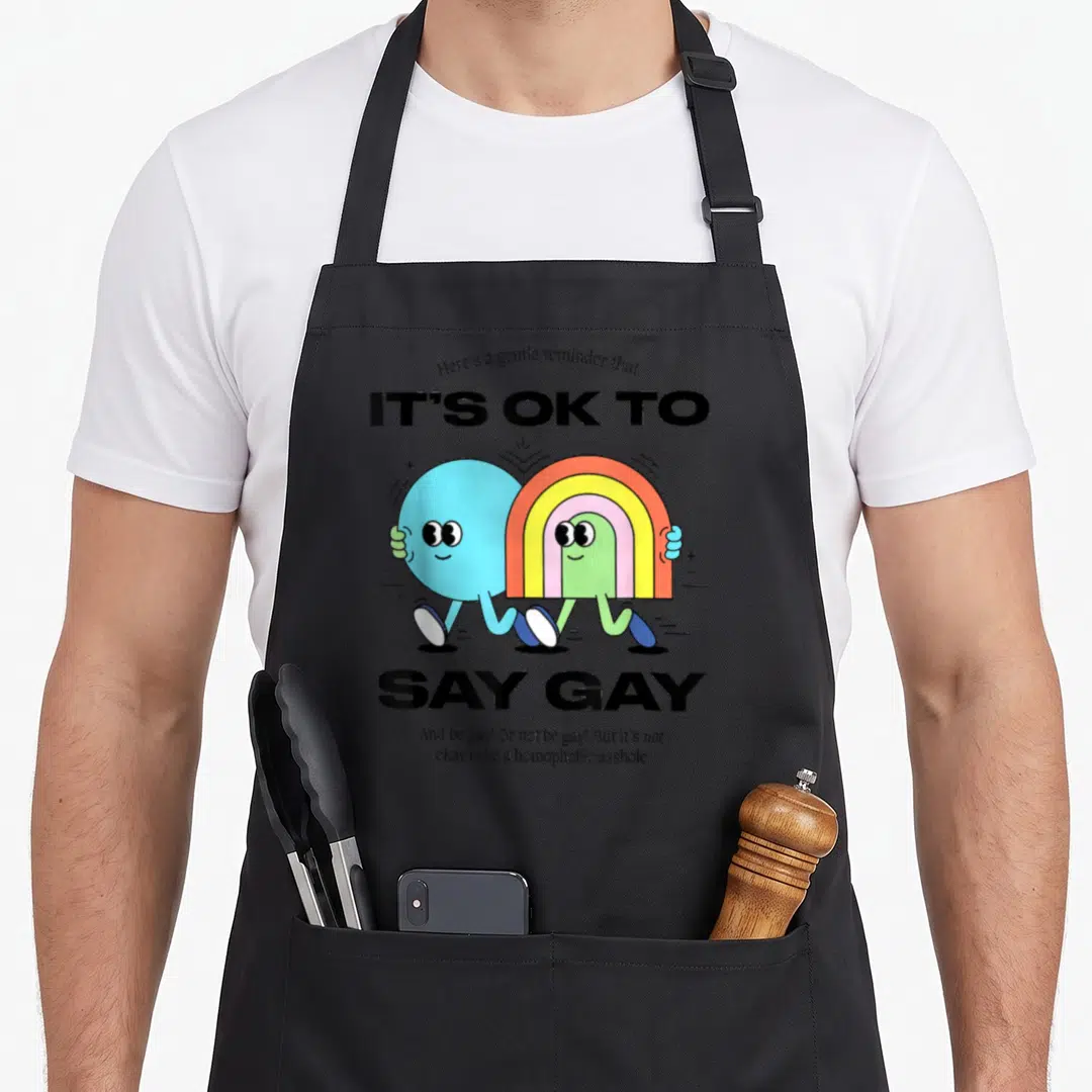 Florida gay pride apron - Cartoon rainbow character walking with blue friend under supportive text — shown on a black cotton canvas apron against a white background