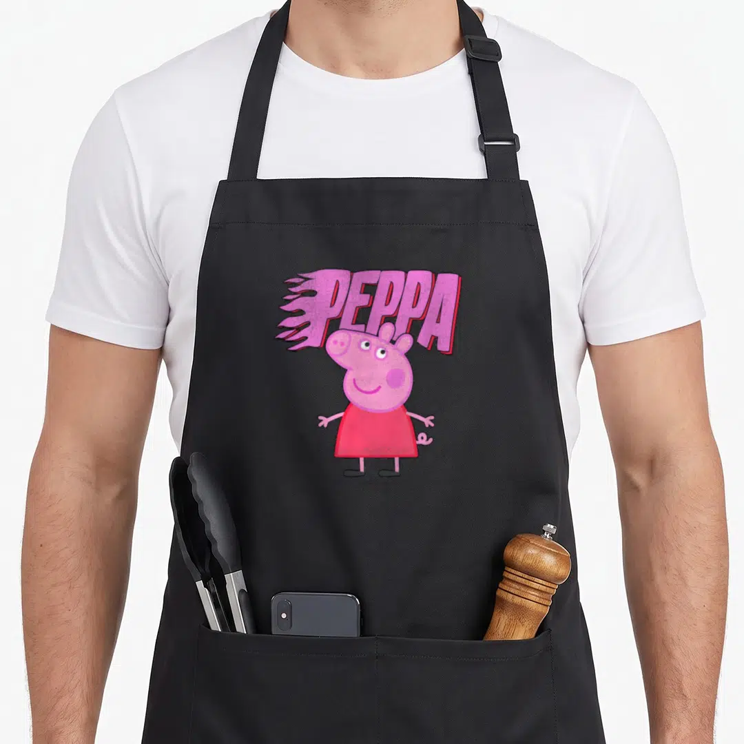 Funny flame apron - Peppa Pig character in red dress below pink text with speed lines on black fabric — shown on a black cotton canvas apron against a white background