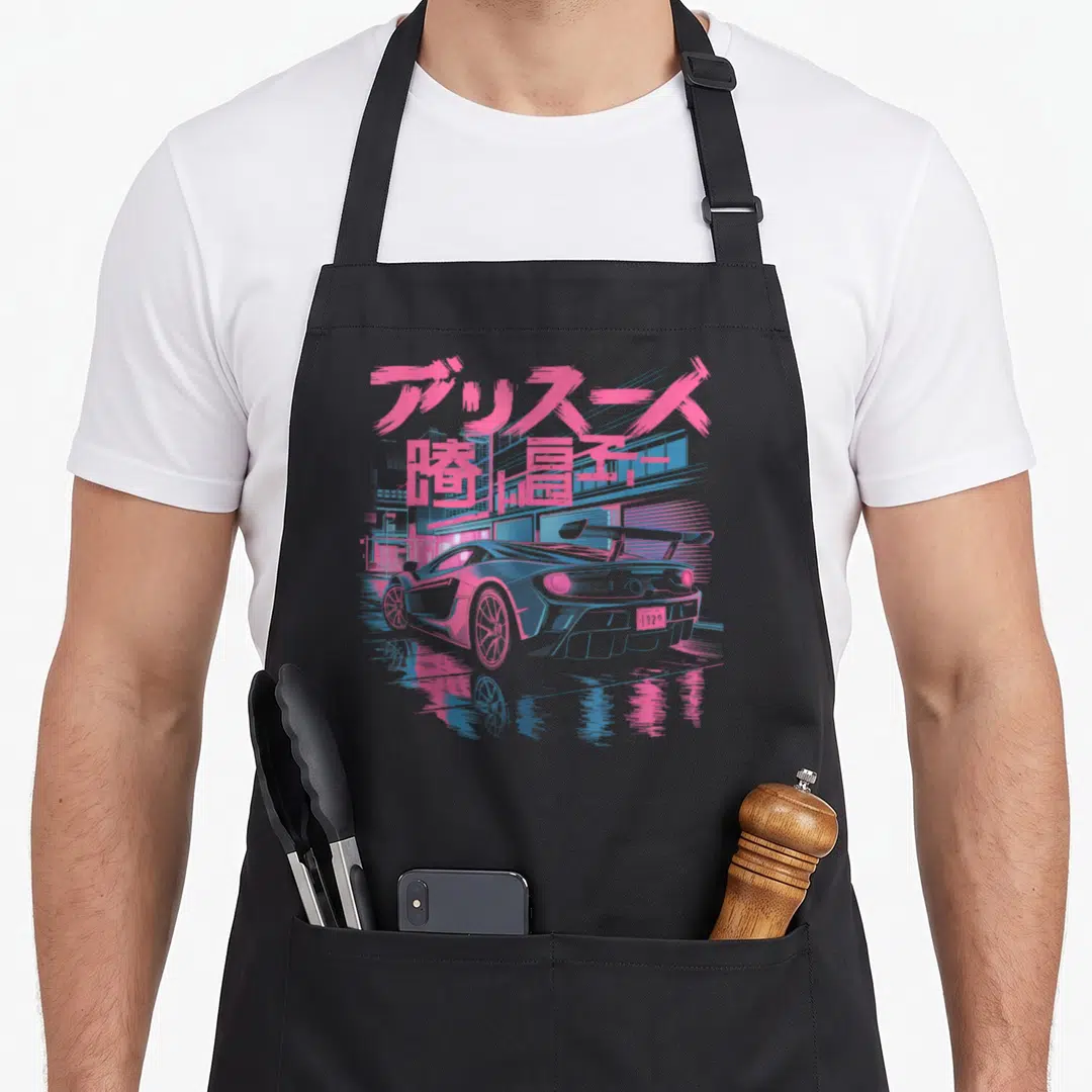Kanji car apron - Pink Japanese text above a grey sports car with blue city background and reflection — shown on a black cotton canvas apron against a white background