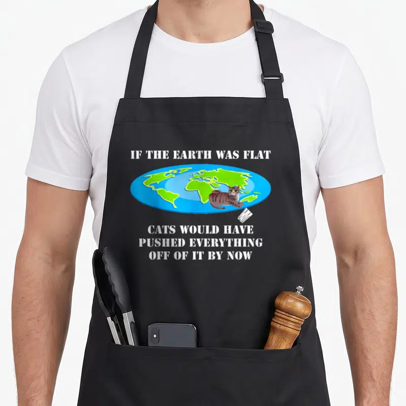 Earth cat apron - Cartoon cat on flat earth map with falling glass and sarcastic white stencil text — shown on a black cotton canvas apron against a white background