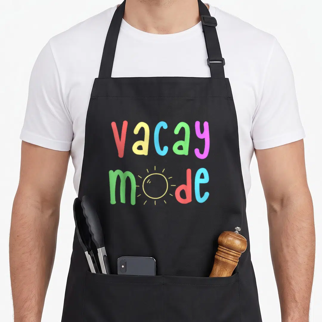 Recreation holiday apron - Multicolored vacay mode text with sun replacing o in two lines — shown on a black cotton canvas apron against a white background